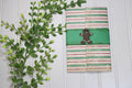 Notebook with gingerbread man design on a white wooden surface with green leaves.